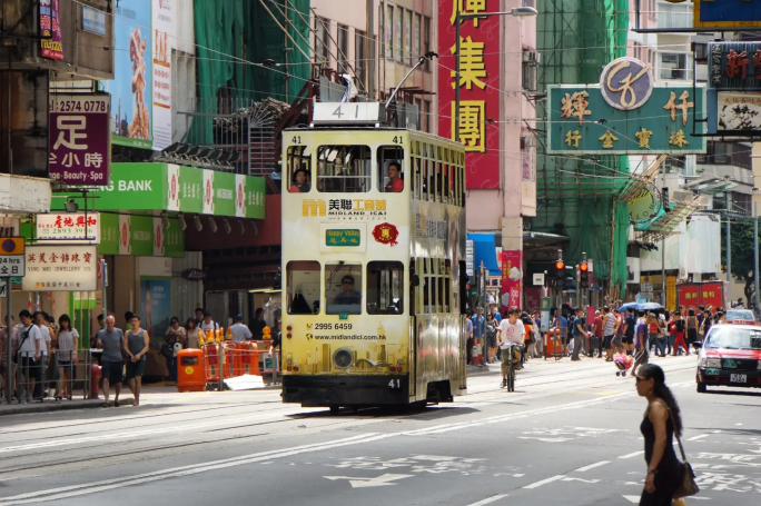 Doppeldecker-Tram fährt durch bunte Straßenschluchten in Hongkong – Cassollage-Reisebild
