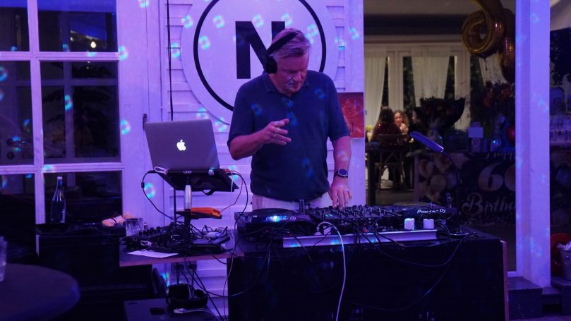Carsten Esser von Cassollage beim Live-DJ-Set am Mischpult unter blau-violettem Partylicht.