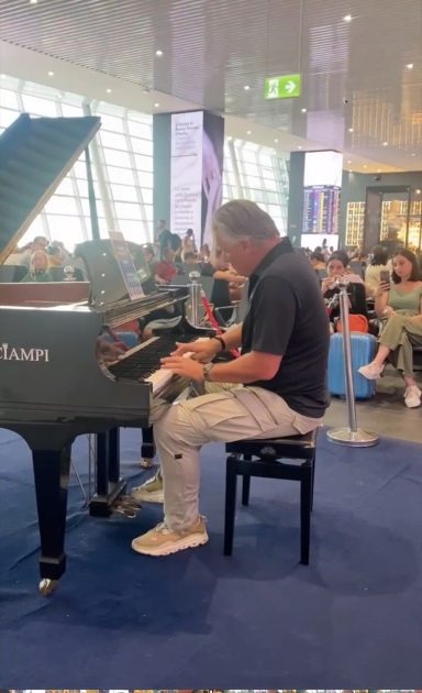 Carsten Esser am Flügel mit Zuhörern im Hintergrund am Flughafen Rom.