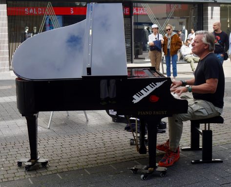 Carsten Esser spielt beim Open Piano auf der Schildergasse, Passanten hören zu.