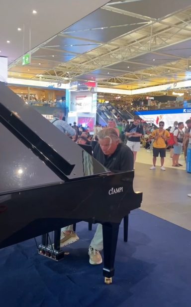 Carsten Esser spielt am schwarzen Flügel in der Flughafenhalle in Rom.