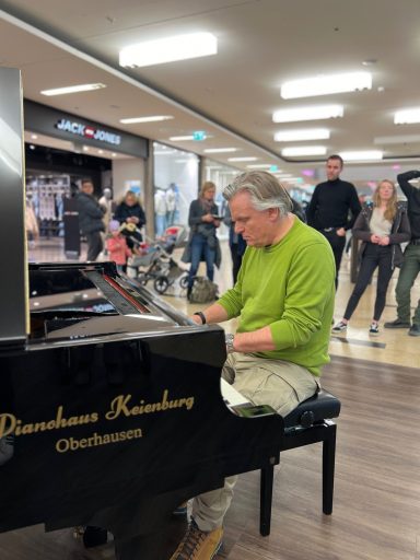 Carsten Esser improvisiert am schwarzen Flügel vor Zuhörern in den Bilker Arcaden.