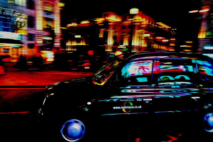 Schwarzes Auto, umgeben von bunten Stadtlichtern bei Nacht.